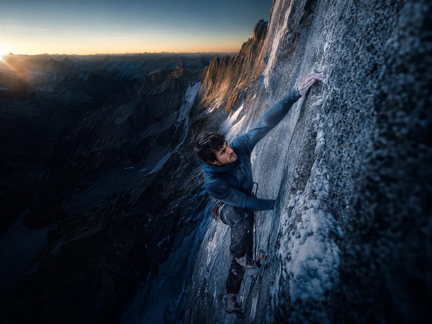 Alpinist mid-move on a steep granite wall at sunrise in the ASCENT layer