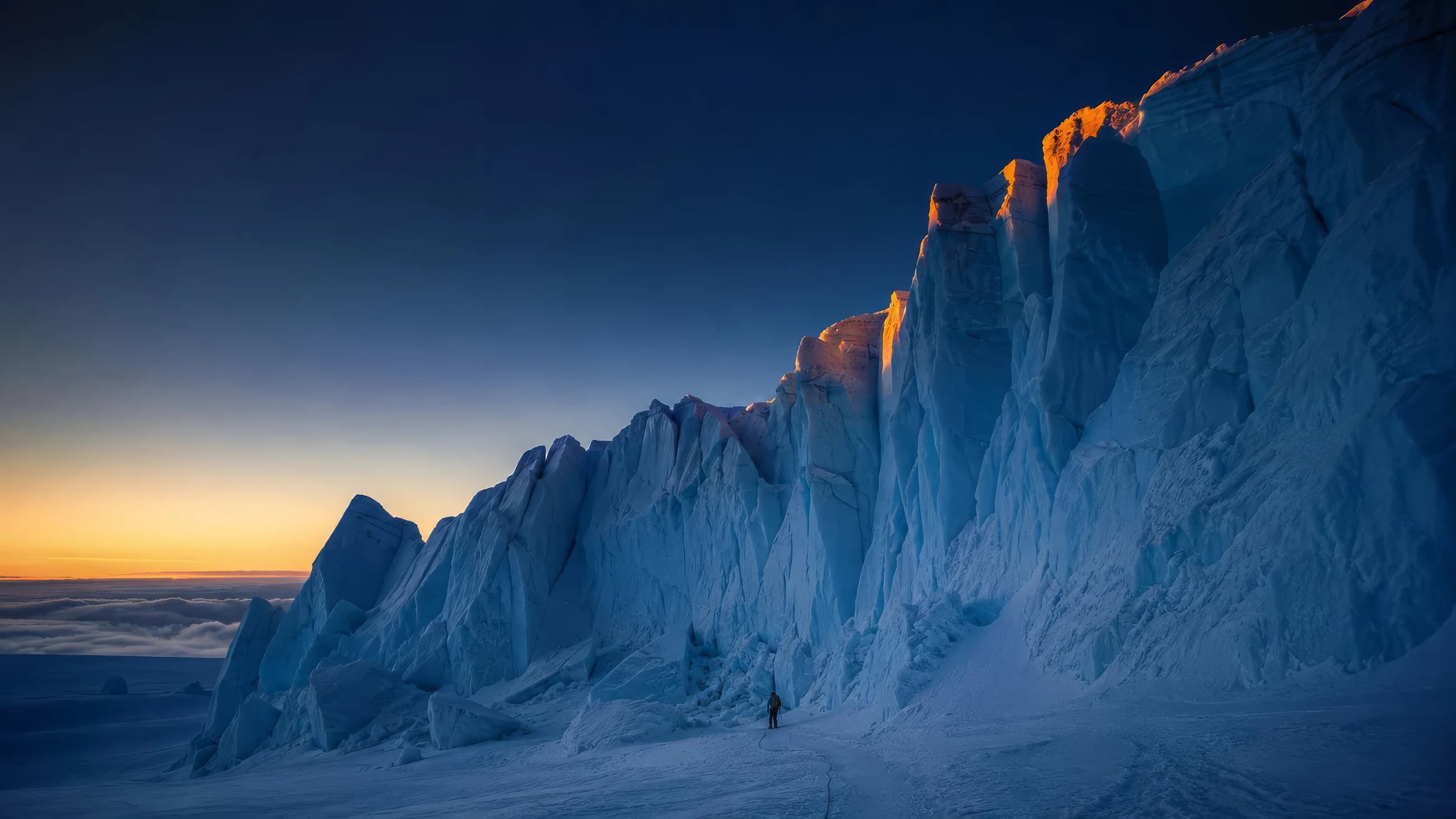 A lone climber at the base of a towering serac wall at dawn